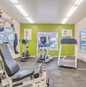 A gym with a variety of equipment including treadmills, weights, and exercise machines.
