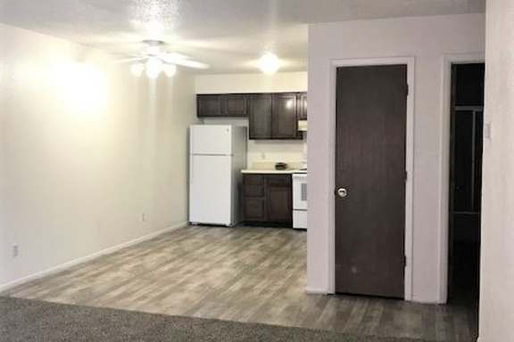 A kitchen with white appliances and wooden floors.