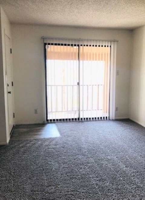 A room with a carpeted floor and a sliding glass door.