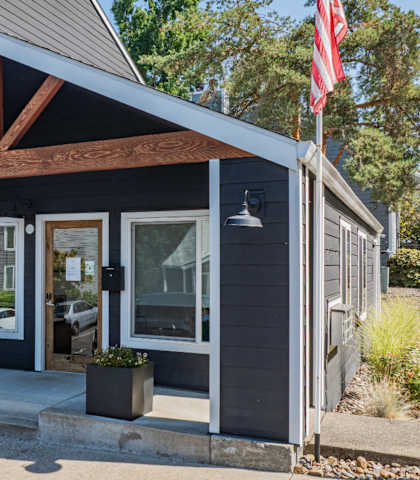 A small building with a porch and a flag on top.