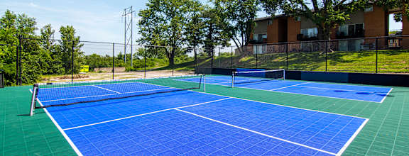 A blue tennis court with a white line down the middle.