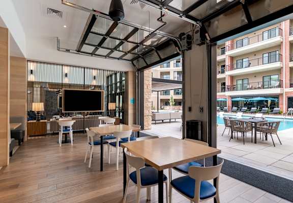 A modern dining area with a television and a view of the pool outside.