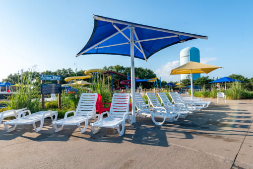 a row of lawn chairs and umbrellas in front of a water park