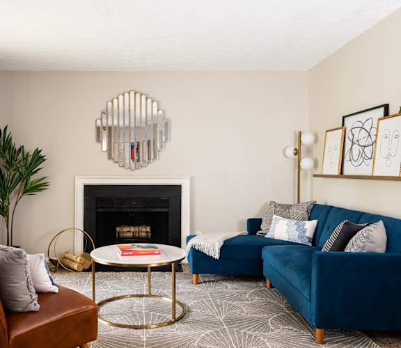 A living room with a fireplace, a blue couch, and a plant.