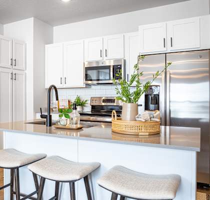 a kitchen with white cabinets and a large island with two stools