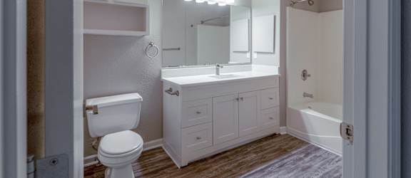 A white bathroom with a toilet, sink, and mirror.
