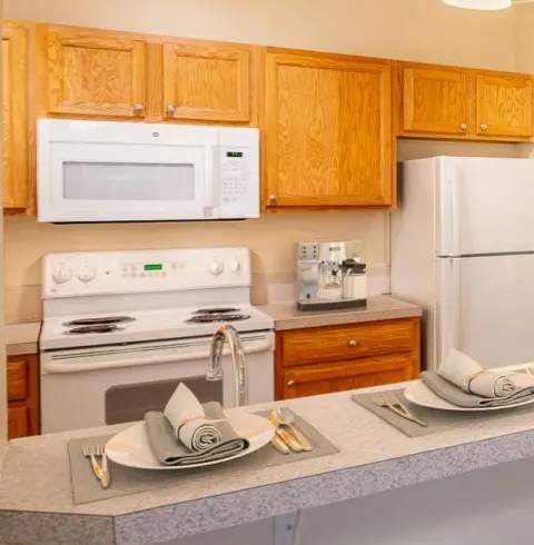 A kitchen with wooden cabinets and a white microwave. at Fairview Village Apartments, Fairview, OR, 97024
