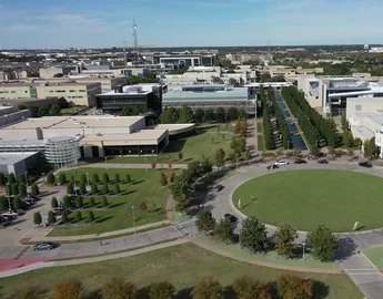 A large building complex with a circular green space in the middle.