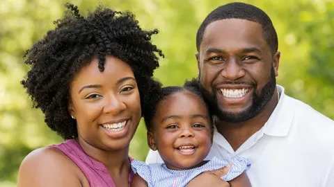 A family of three is smiling and enjoying a sunny day outdoors.