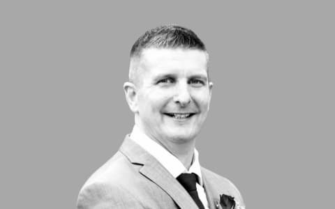 A man in a suit with a flower on his lapel.