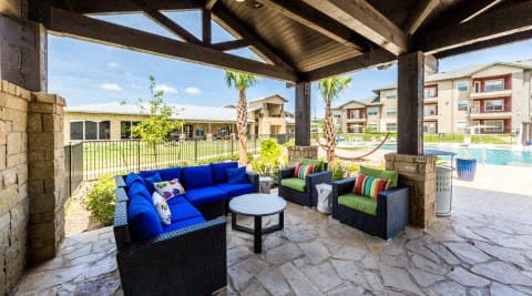 a covered patio with blue couches and a coffee table at Legacy Creekside Apartments, San Antonio