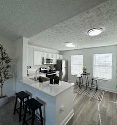 A kitchen with white countertops and black stools.