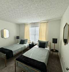 Two twin beds in a room with a mirror and a window.