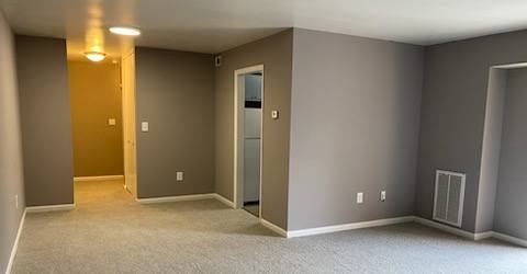 an empty room with gray walls and a white carpet