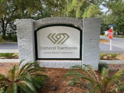 A sign for Diamond Townhomes is displayed in front of a stop sign at Diamond Townhomes, Beaufort, SC 29906