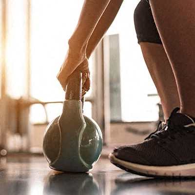 A person is about to lift a kettlebell in a gym.