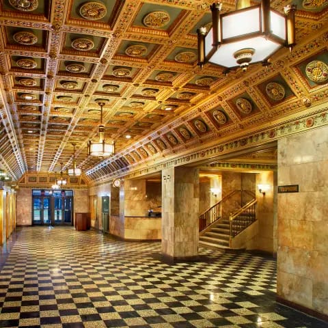the lobby of a building with a checkered floor and a staircase