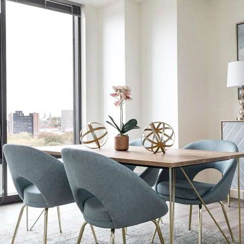 A dining table with grey chairs and a vase with a flower on it.