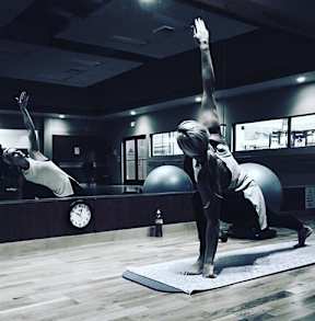 Two people doing yoga in a dimly lit room.
