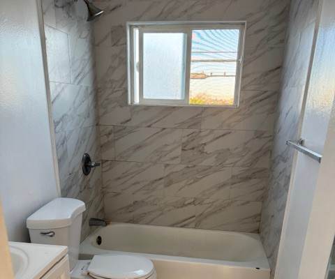 A bathroom with a tub, toilet and sink.