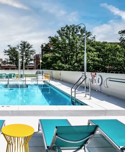 a swimming pool and a poolside patio with a yellow table and chairs