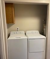 A white microwave oven is placed above a white fridge in a kitchen.