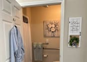 Thumbnail 1 of 9 - A bathroom with a toilet, a shower curtain, a towel, and a robe hanging on the door.