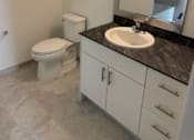 Thumbnail 2 of 7 - A bathroom with a toilet, sink, and mirror.