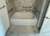Thumbnail 3 of 7 - A white bathtub with a shower curtain rod above it.