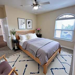 A bedroom with a bed, a chair, and a ceiling fan.