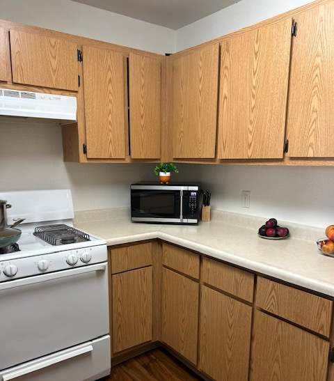 A kitchen with wooden cabinets and a white stove top.
