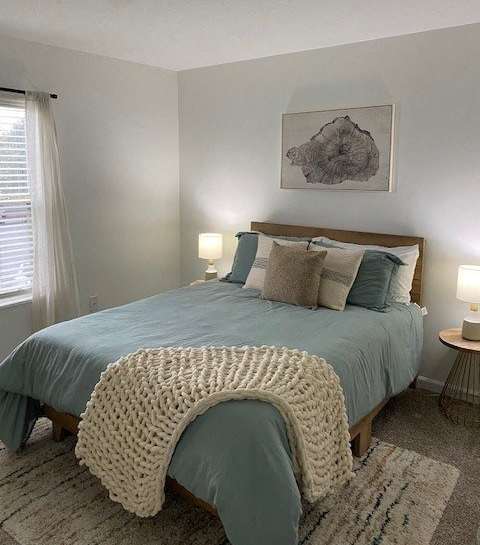 A bedroom with a bed covered in a blue comforter and a white knitted throw.
