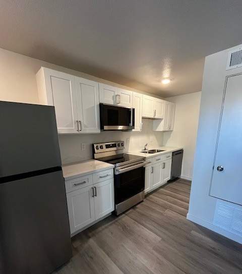 A kitchen with a black fridge and white cabinets.