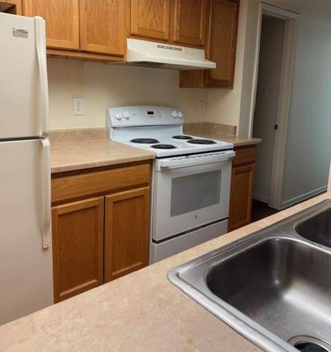 A kitchen with a white refrigerator, white stove, and a sink at Ascent on Spence, Tempe Arizona