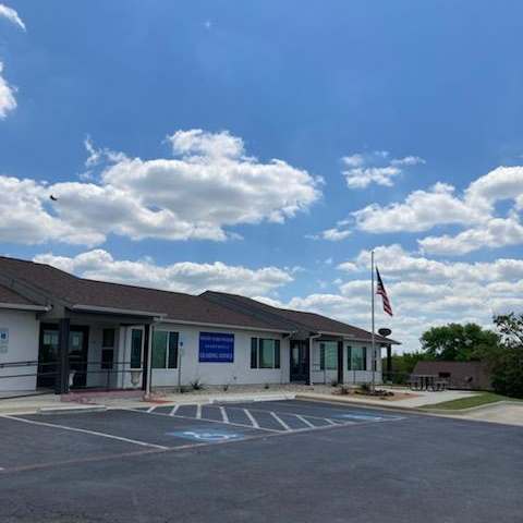 A building with a flag on top and a parking lot in front.
