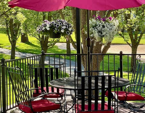 A table with chairs and an umbrella is on a patio.