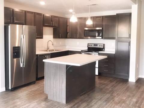 A modern kitchen with a refrigerator, microwave, oven, and sink.