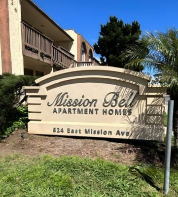 a sign that is in the grass with a building in the background