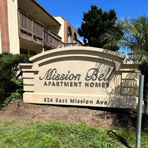 a sign that is in the grass with a building in the background