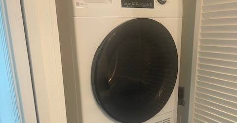 A white front loading washing machine in a small room.