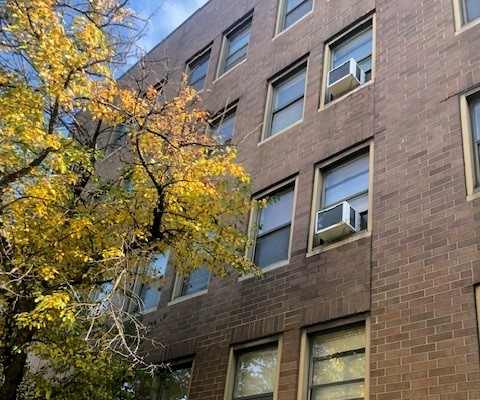 A brown building with a tree in front of it.