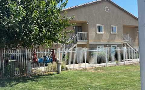 A house with a white fence and a tree in front.