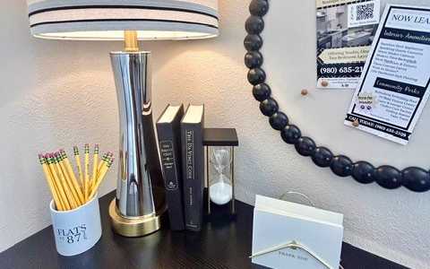 A desk with a lamp, pencils, books, and a card holder.