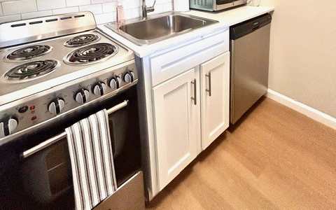 A kitchen with a stove, sink, and microwave.