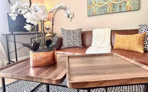 A living room with a brown sofa, a coffee table, and a painting on the wall.
