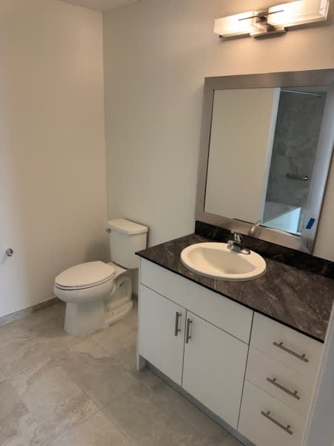 A bathroom with a toilet, sink, and mirror.