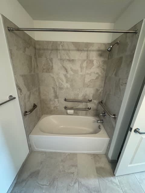 A white bathtub with a shower curtain rod above it.