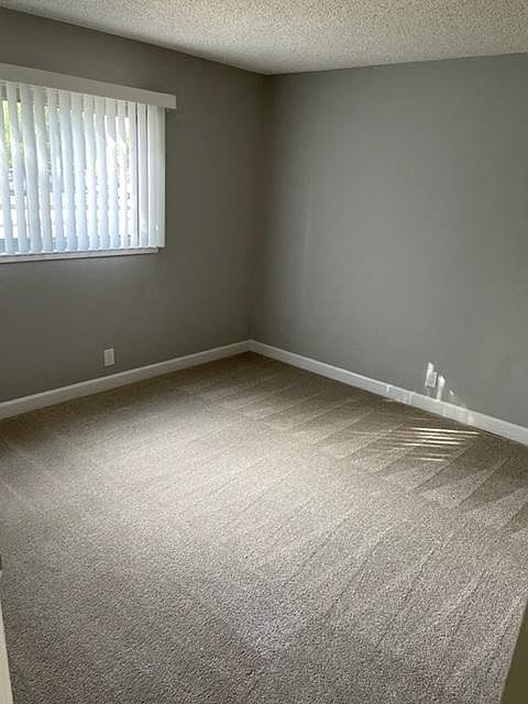A room with a carpeted floor and a window with blinds.