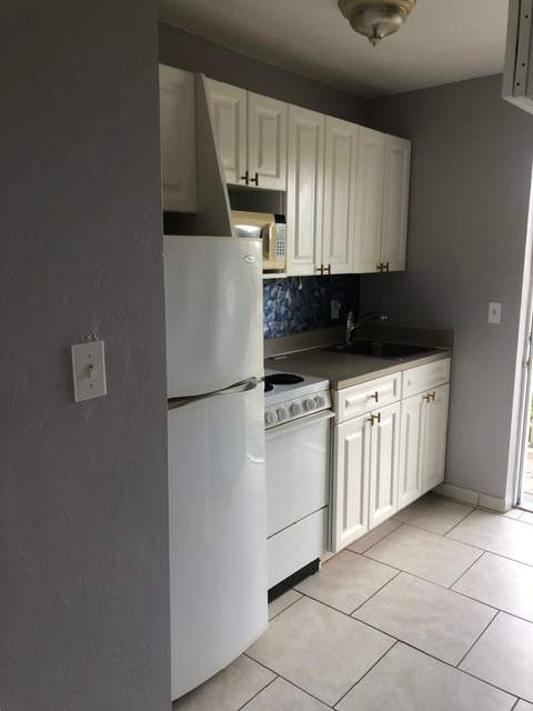 A white refrigerator is in a kitchen with a white door.