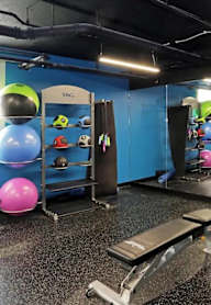 A gym with a variety of equipment including a bench, a ball, and a rack with weights.